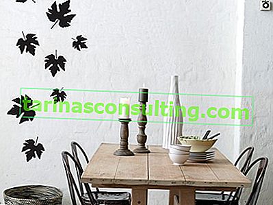 Holztisch, schwarze Stühle, schwarze Blätter an der Wand, weiße Vase