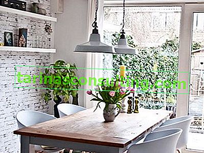 cihlová zeď v jídelně, bílé stěny, bílá závěsná lampa, bílé židle, dřevěný stůl