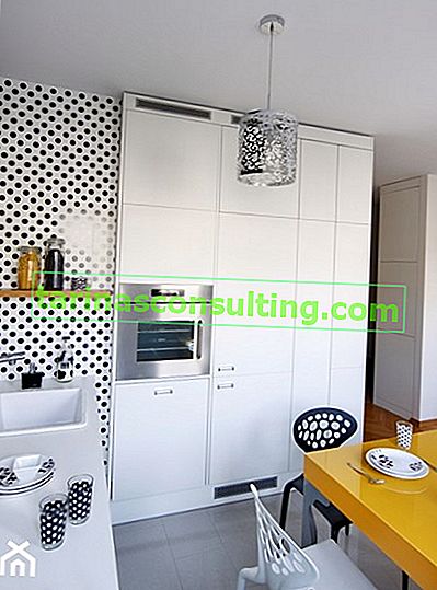 weiße Tapete mit schwarzen Punkten in der Küche, eingebauter Geschirrspüler, weiße Küchenmöbel, gelber Tisch