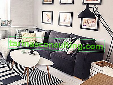 ein schwarzes Sofa in einem hellen skandinavischen Wohnzimmer